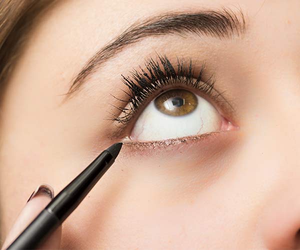 woman putting on eyeliner