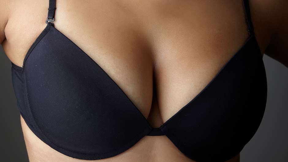 Looking down on female woman in only bra with ample breasts