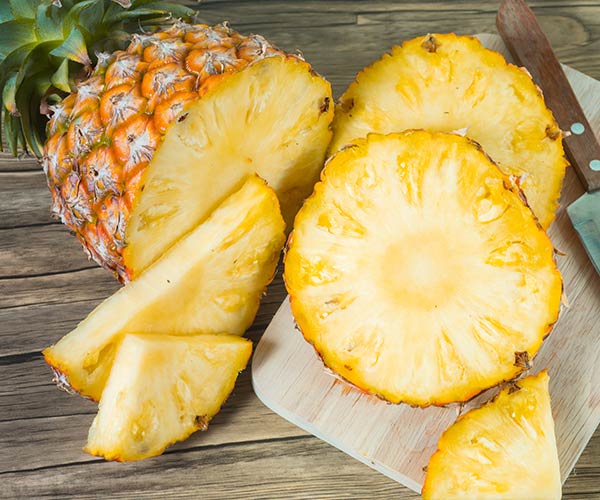 pineapple cut up into slices on table