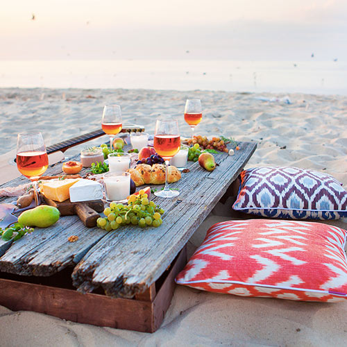 beach picnic table with food and floor pillows