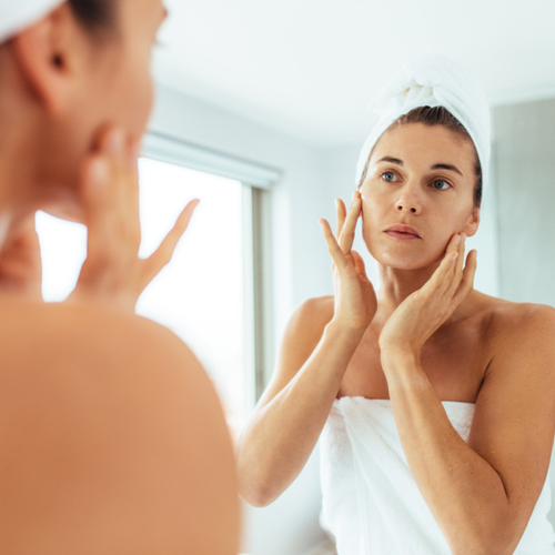 woman checking face in mirror