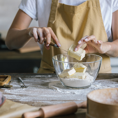 A person putting margarine into a bowl.