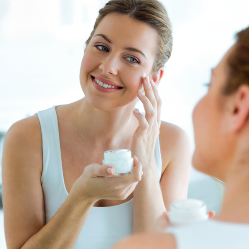 woman putting lotion on her face