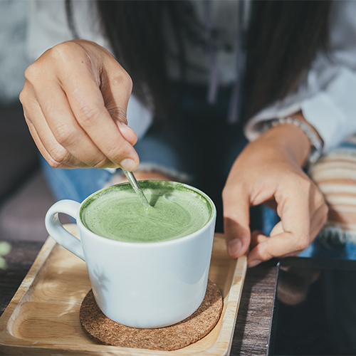 A person stirring a cup of matcha tea.