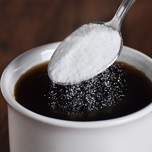 sugar on spoon into coffee