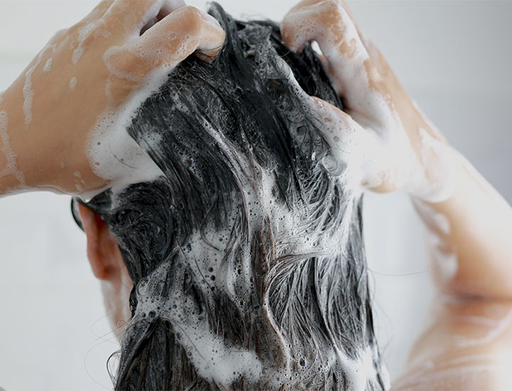 Woman washing hair with shampoo.