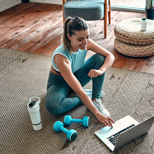 woman sitting on floor with weights and laptop