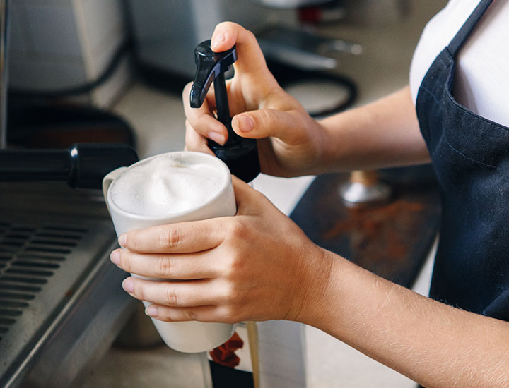 Person pumping syrup into coffee