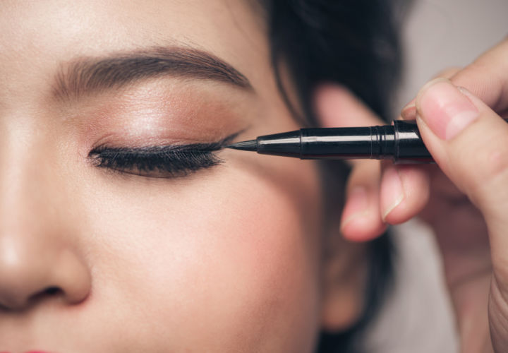 Woman applying eyeliner.