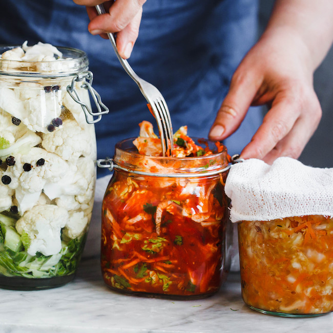 woman adding fermented foods to jars