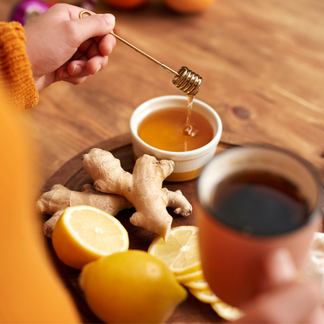 ginger tea mugs sliced ginger cutting board teacups hand mixing tea