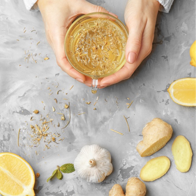 hands holding ginger tea herbs spices table sliced ginger lemons garlic preparing tea