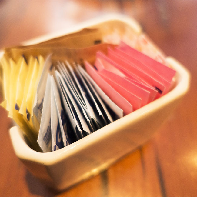 packets of artificial sweetener in holder on table