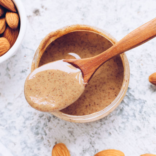 jar of almond butter with spoonful on top