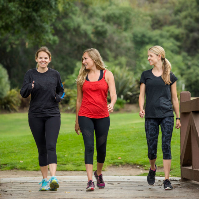 three women walking on bridge outside