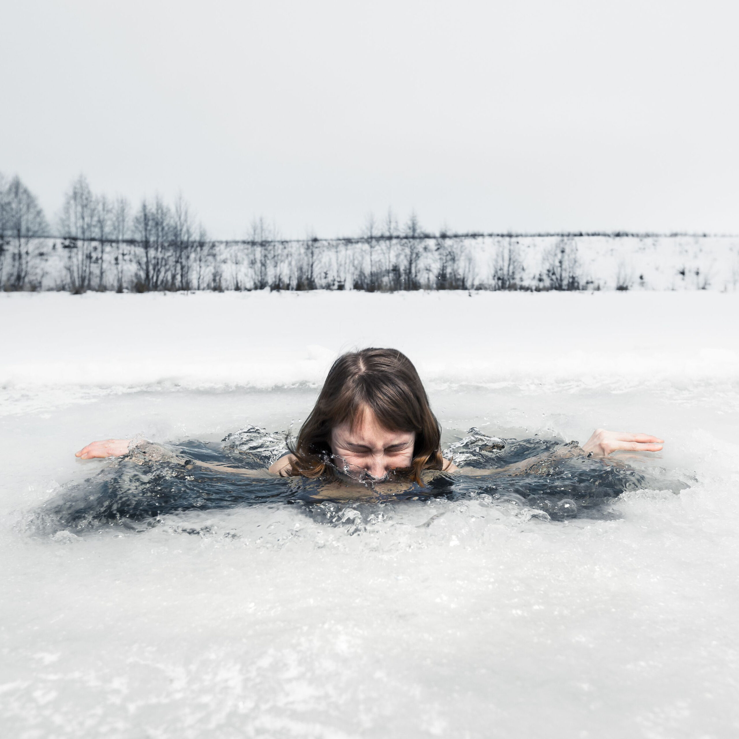 woman submerging herself in ice water outdoors in the winter