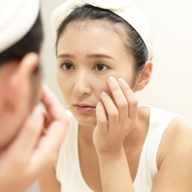 woman looking in mirror at eyes fine lines