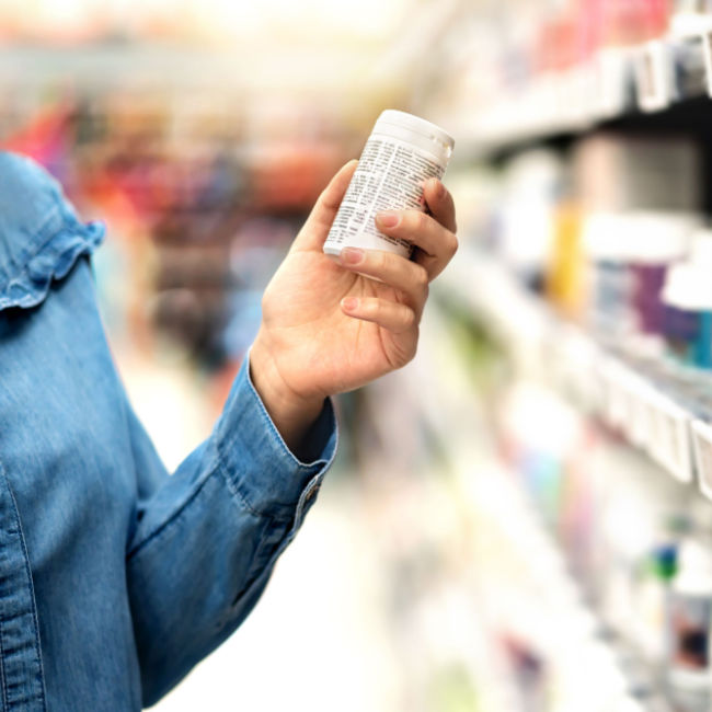 person inspecting supplement bottle in grocery store