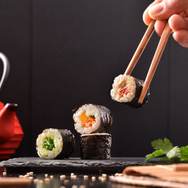 person eating sushi with chopsticks