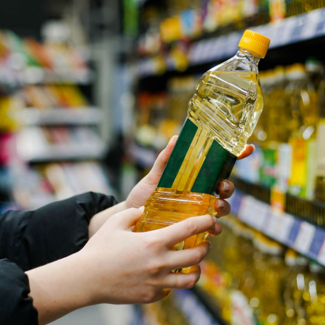 Une femme ramasse de l'huile dans une épicerie