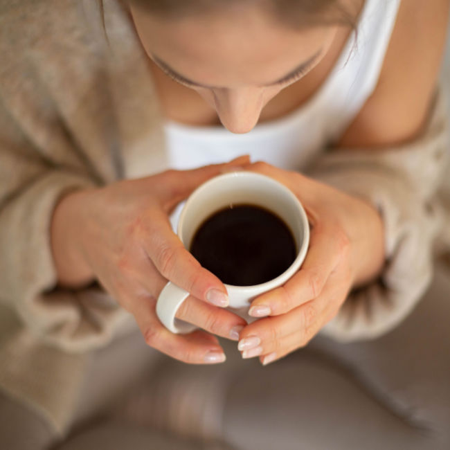 woman drinking mug of black coffee