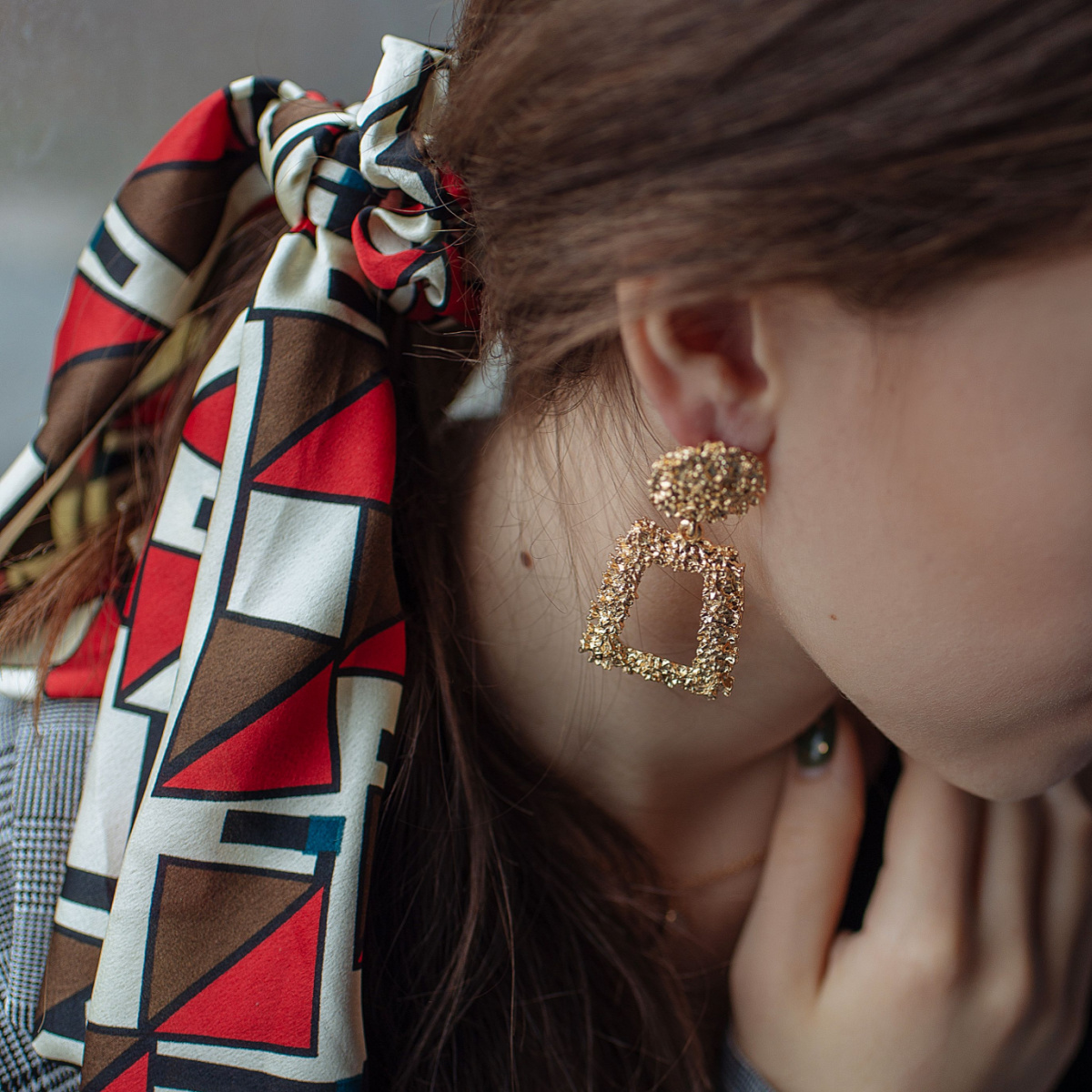 woman hair tied scarf ponytail dangly gold earrings