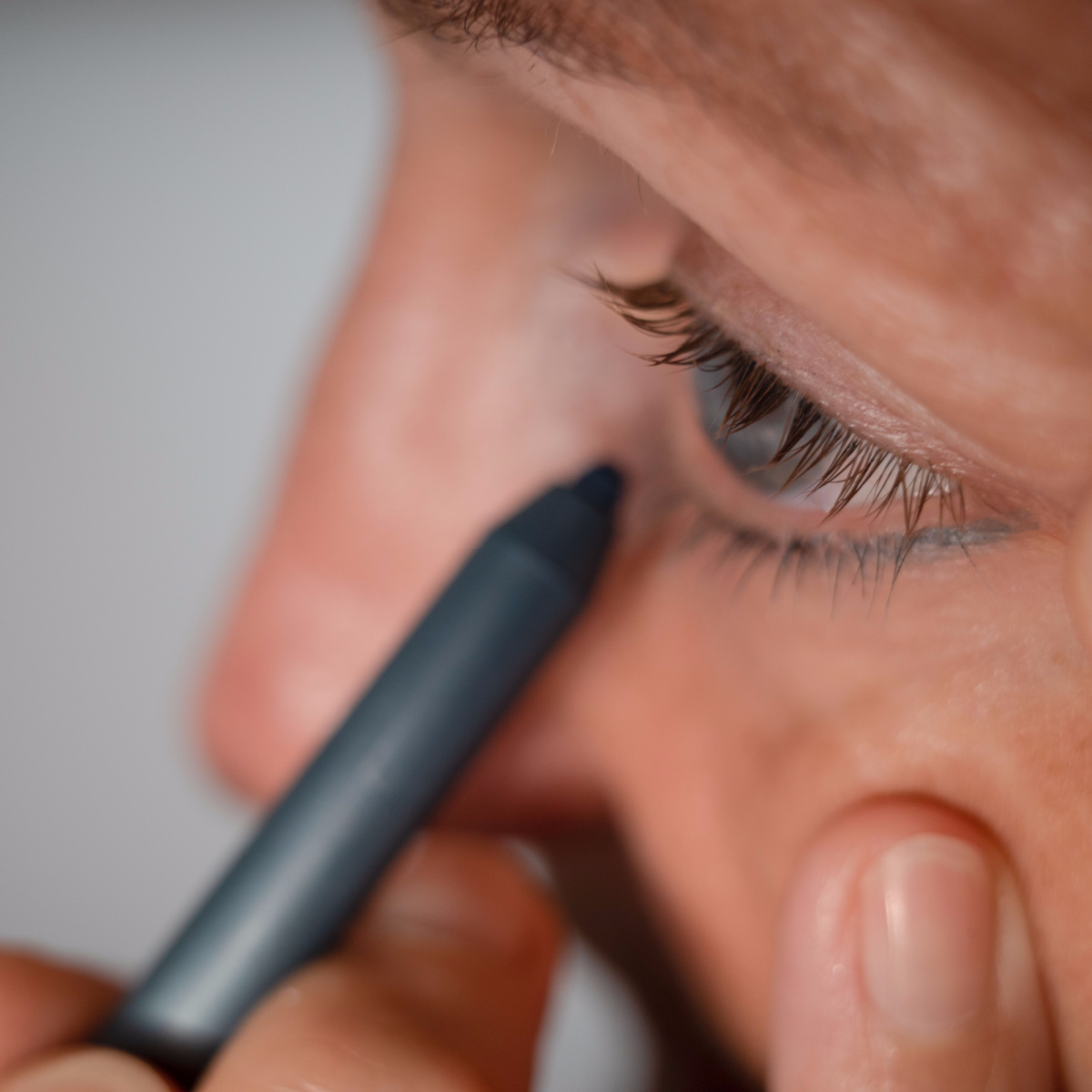 woman applying blue eyeliner to bottom lid close up