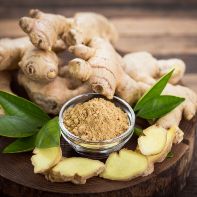 ground ginger in small glass dish beside ginger root