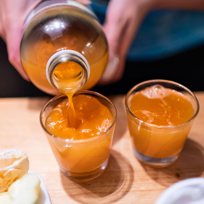 bottle of kombucha being poured into two glasses