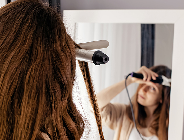 Woman styling hair with curling iron.