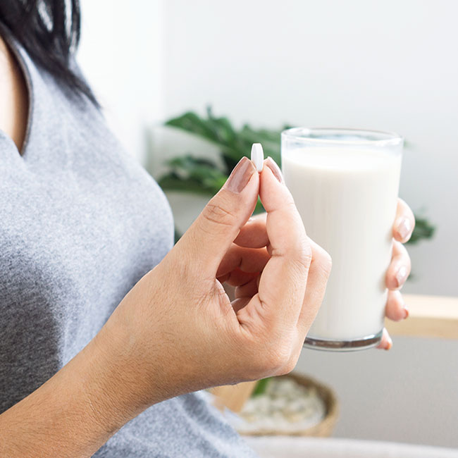 woman taking pill with a glass of milk