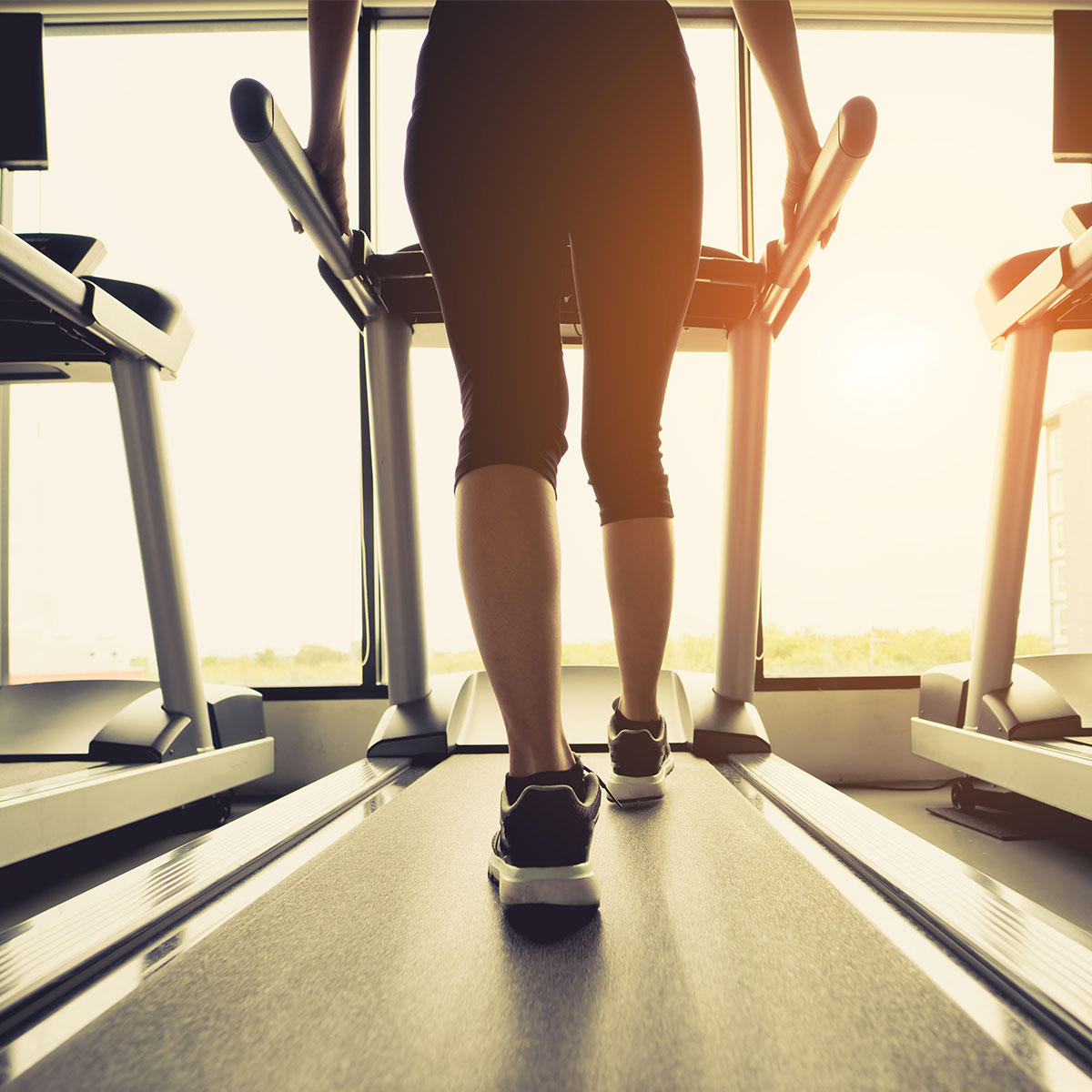 legs of woman walking on treadmill at gym