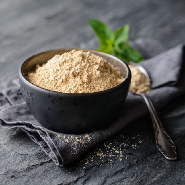 bowl of maca powder next to spoonful