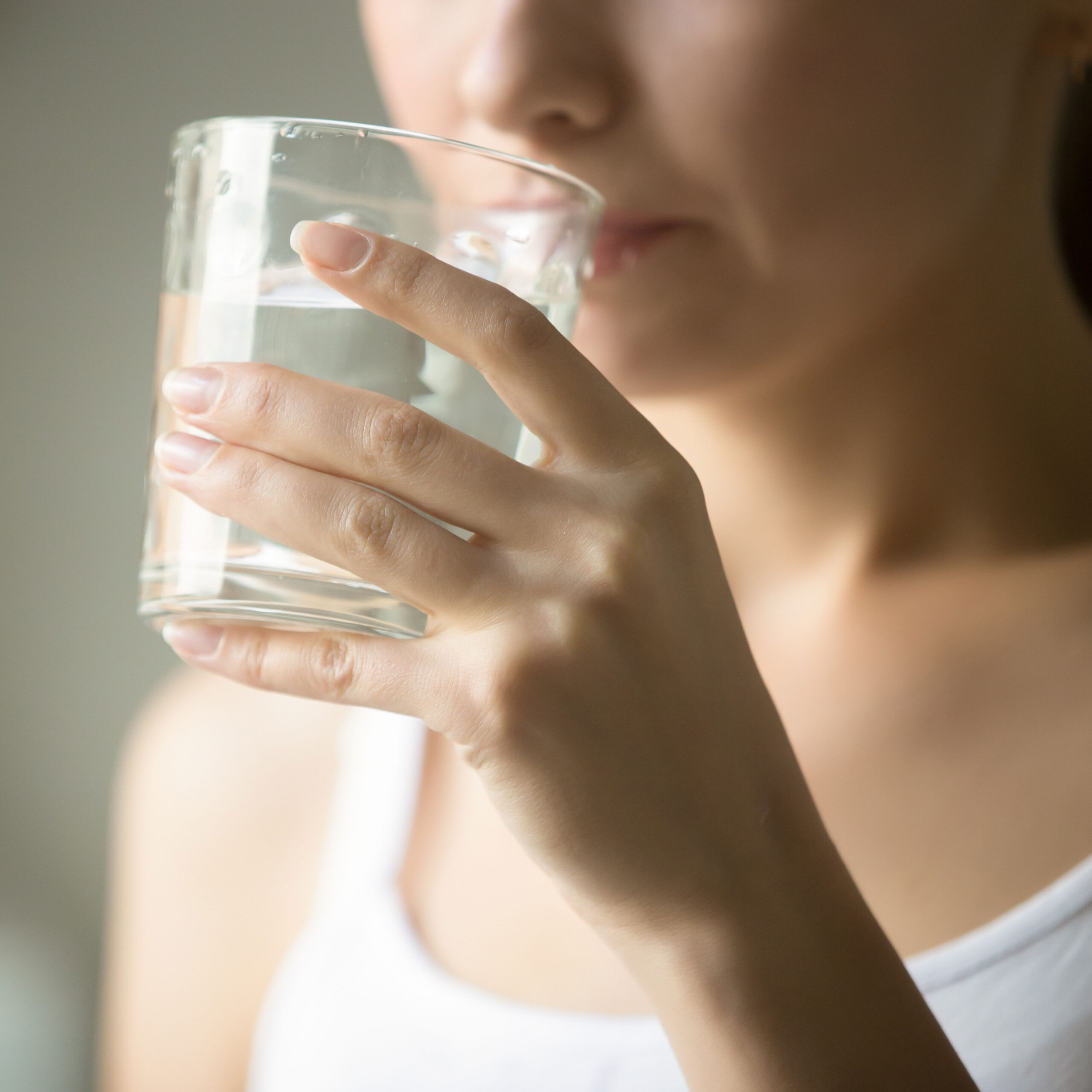 woman holding glass of water to mouth