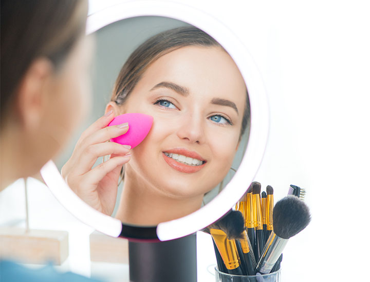 woman-applying-makeup-vanity-mirror