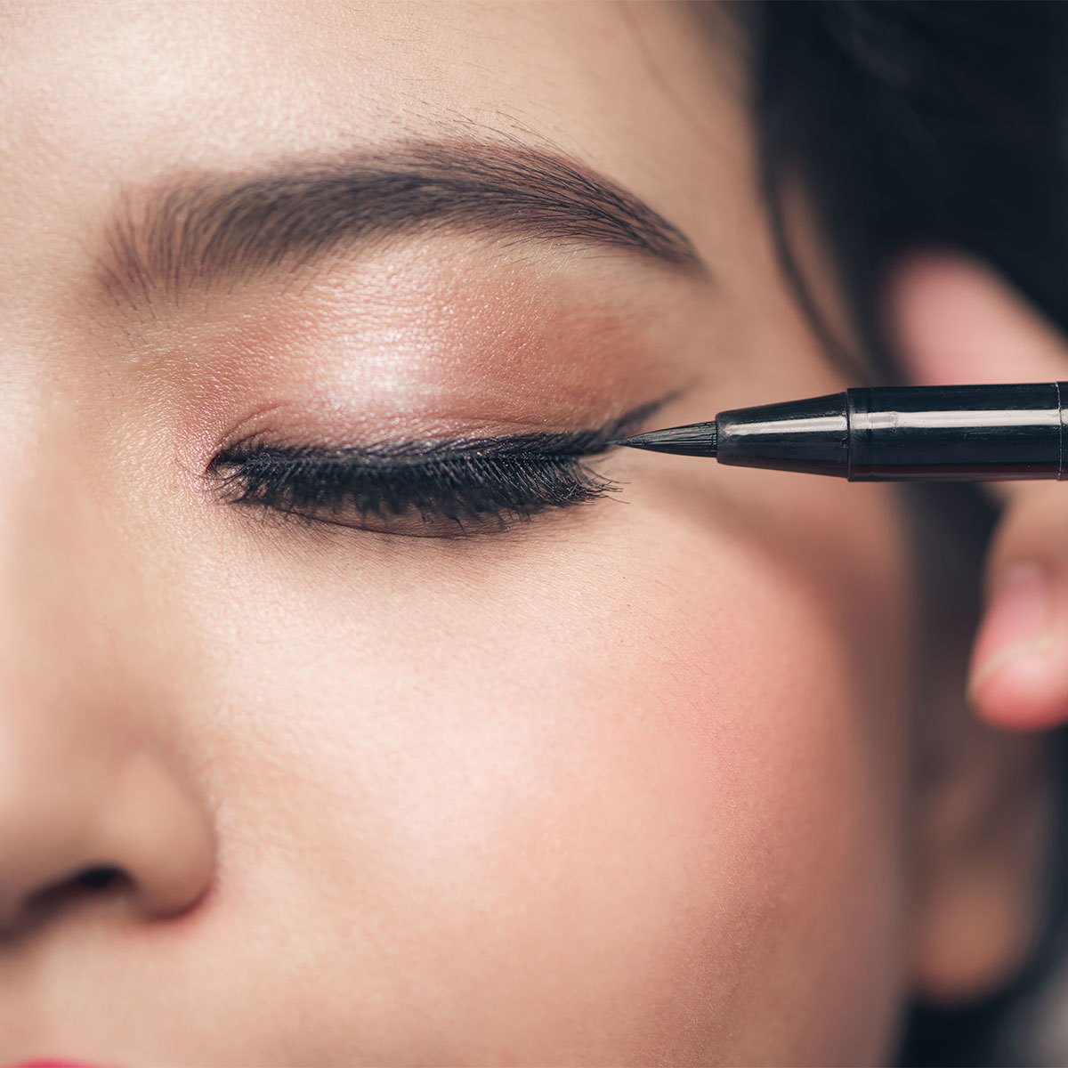 woman creating eyeliner wing liquid liner close-up