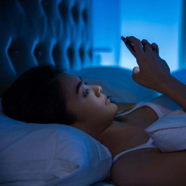 woman using phone in bed