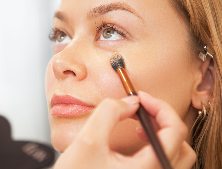 Woman applying makeup under eyes