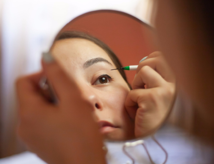 Woman applying eye makeup in a mirror