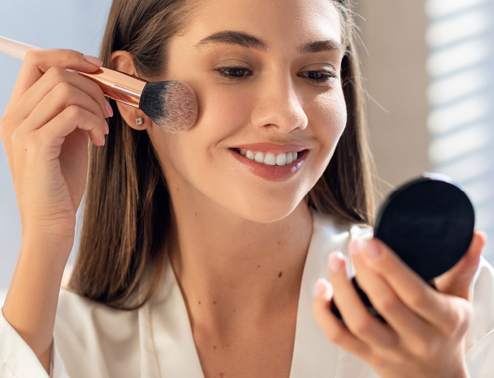 Woman applying blush to cheekbones