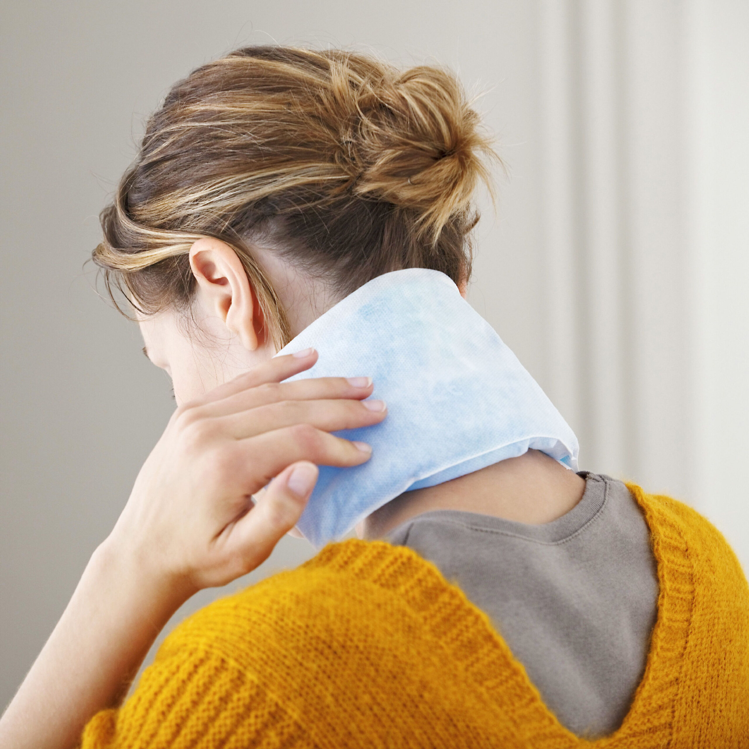 woman with heating pad on back of neck