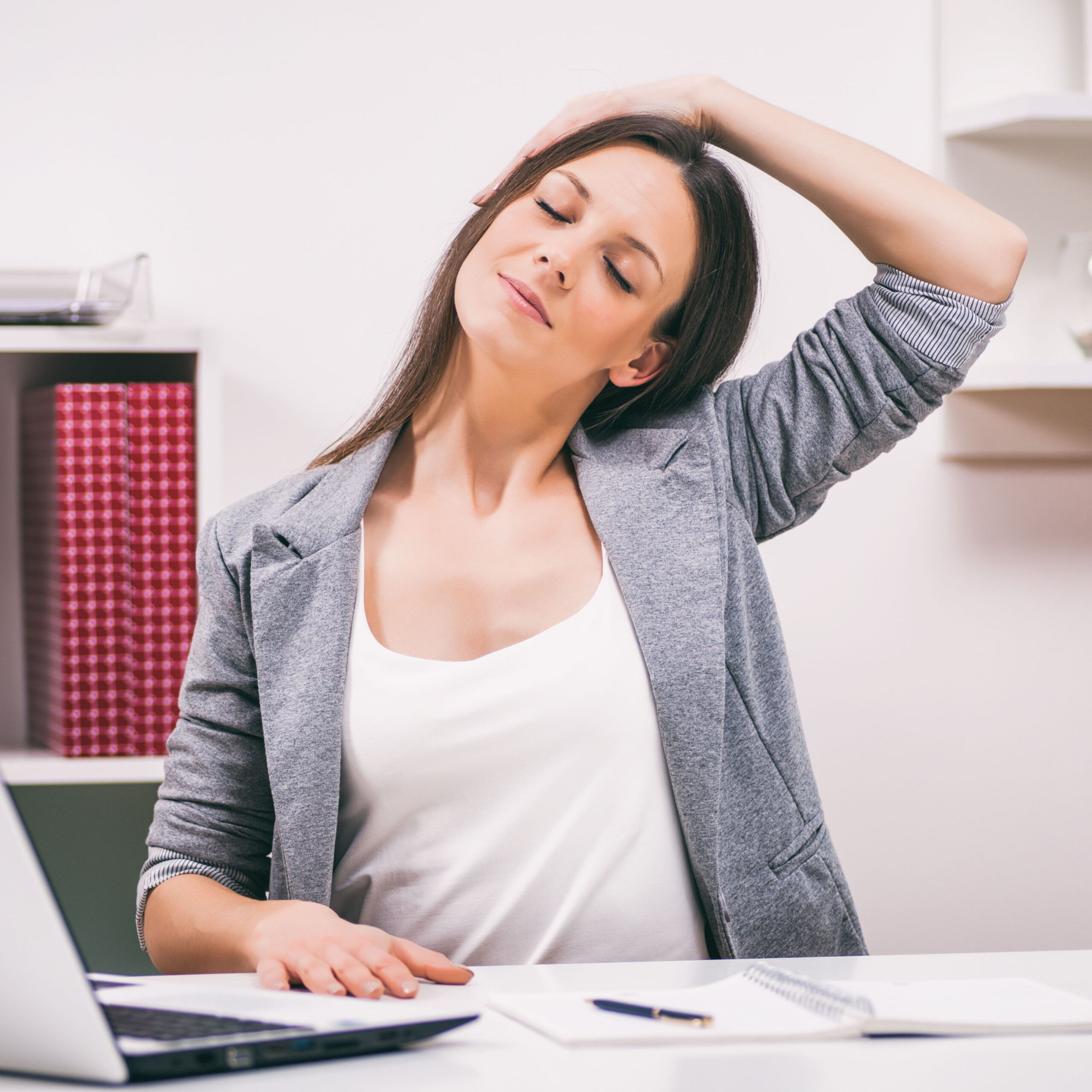 woman stretching neck at desk