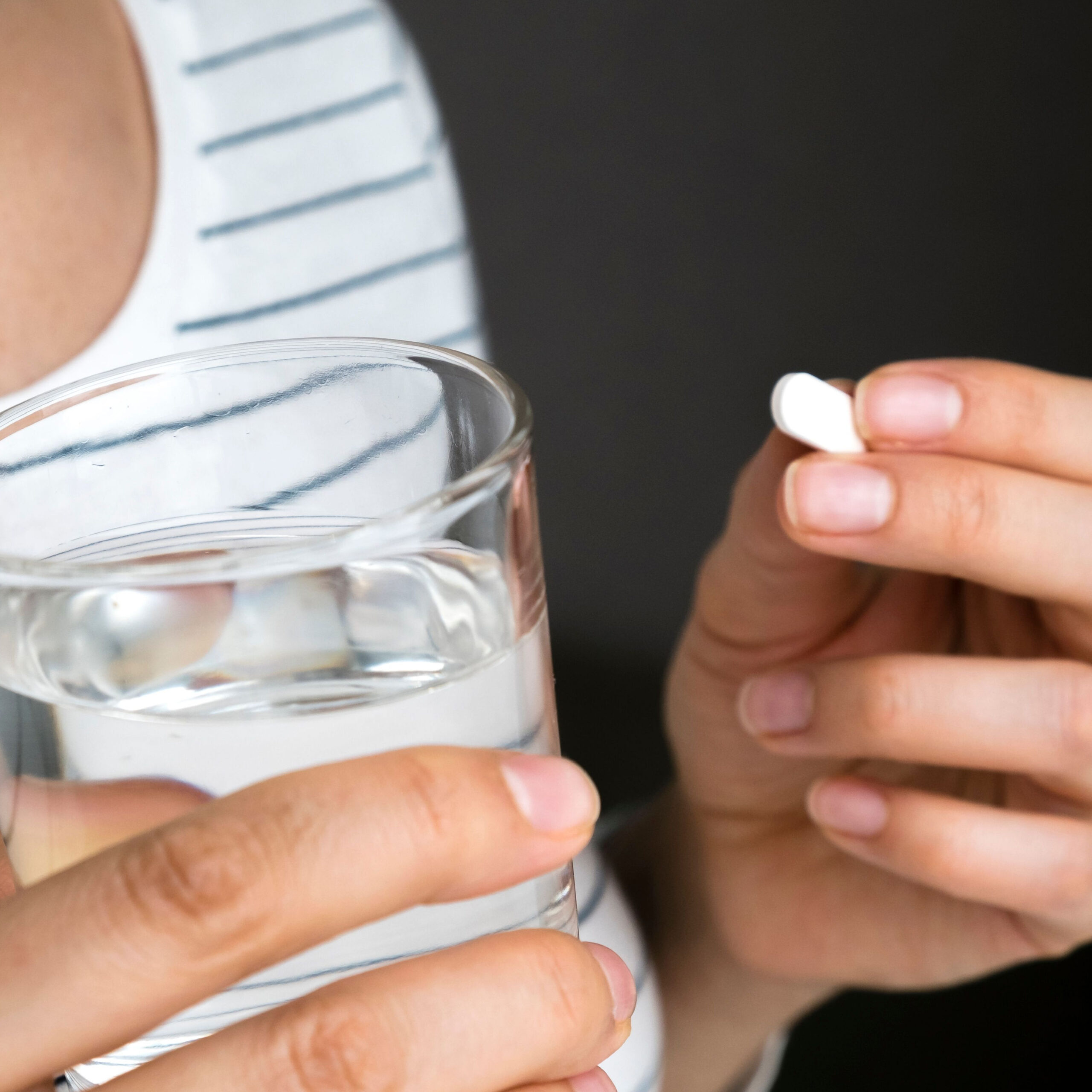 woman holding painkiller and glass of water