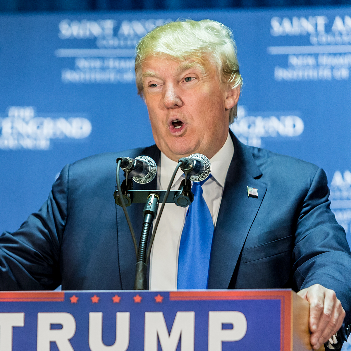 donald trump blue tie speaking orange skin yellow hair rally podium microphone