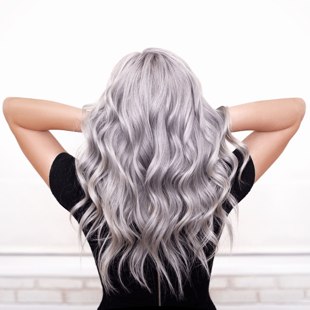 woman running hands through wavy gray hair black shirt hands in hair