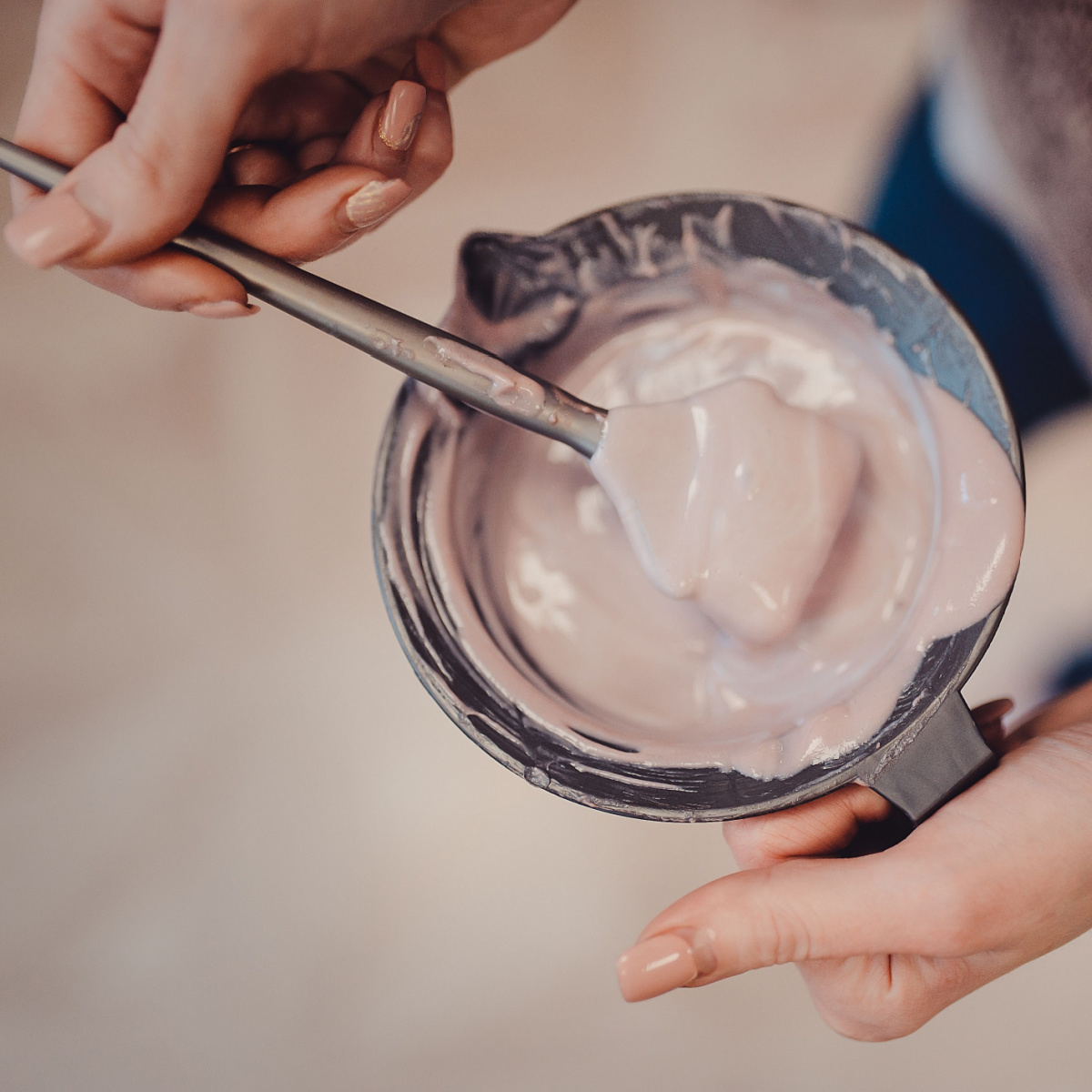 hair stylist mixing dye for hair in bowl at salon