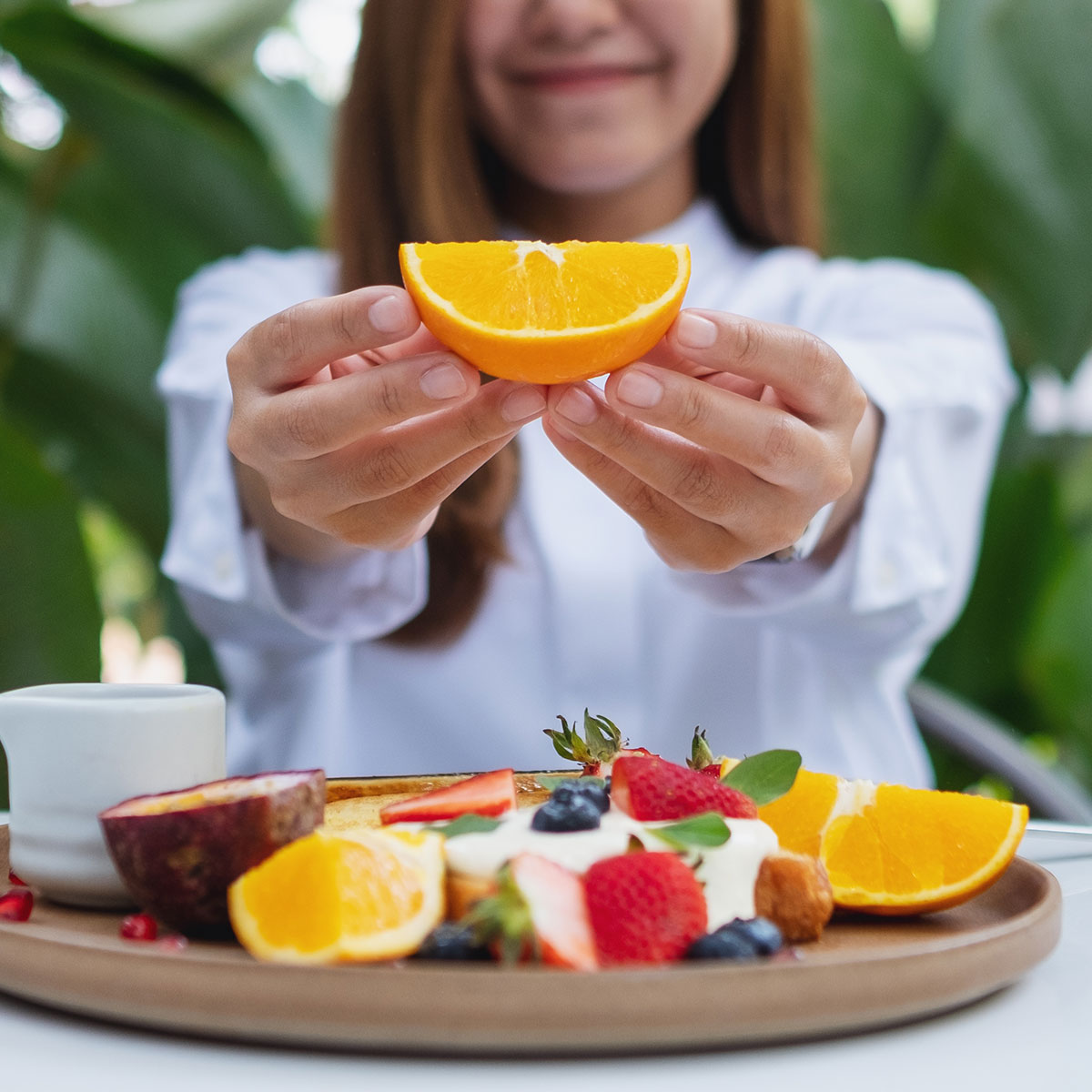 woman eating oranges and berries outside