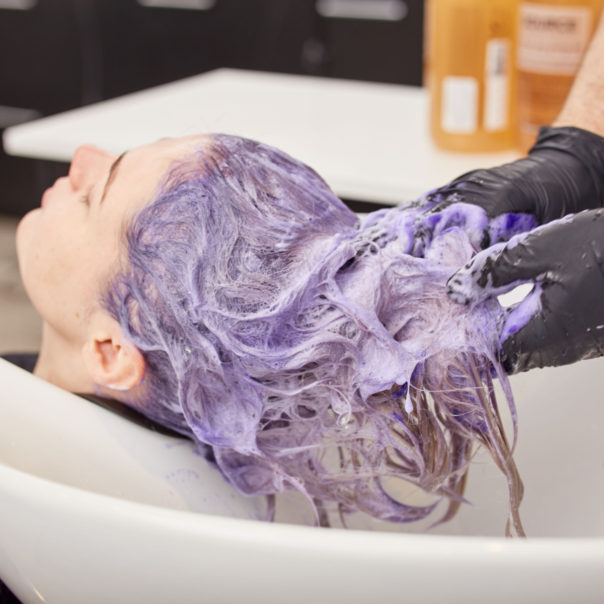 hair stylist applying purple toner shampoo cleanse rinse hair sink salon