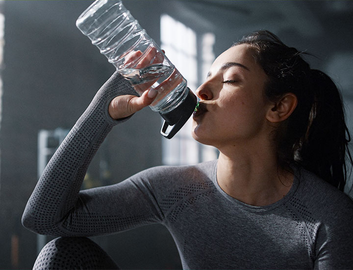 Woman drinking water bottle at gym