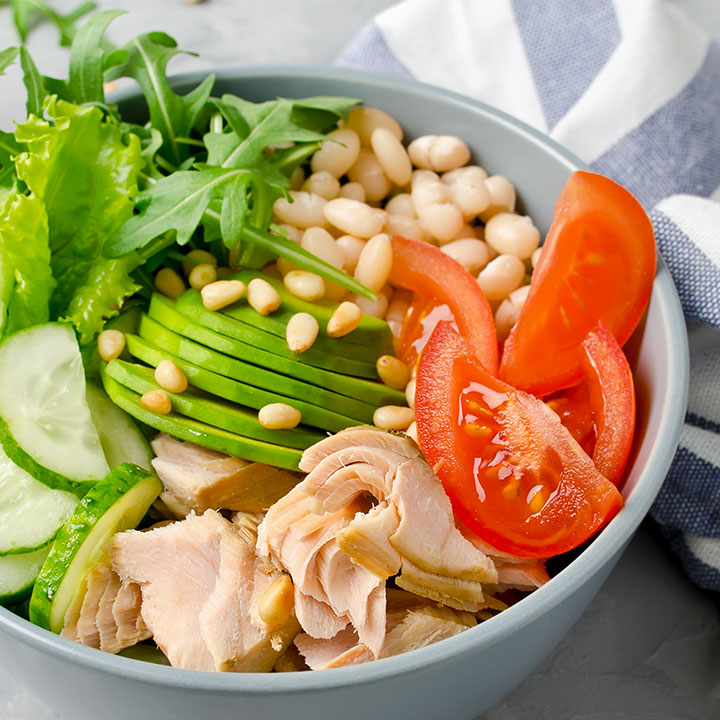 healthy salad bowl with white beads, avocado, cucumber, tomato, pine nuts, and meat